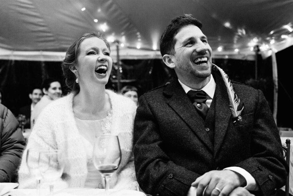 The bride and groom both laugh at their wedding speeches